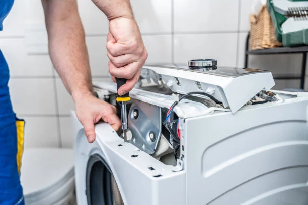 Close-up of a technician checking washing machine connections and internal components