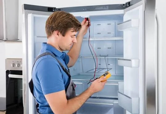 Technician testing cooling components inside a refrigerator-freezer