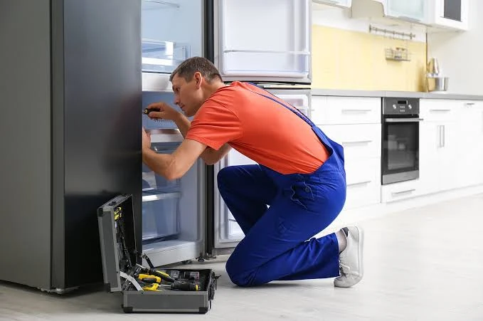 Technician working inside a refrigerator in a bright home kitchen